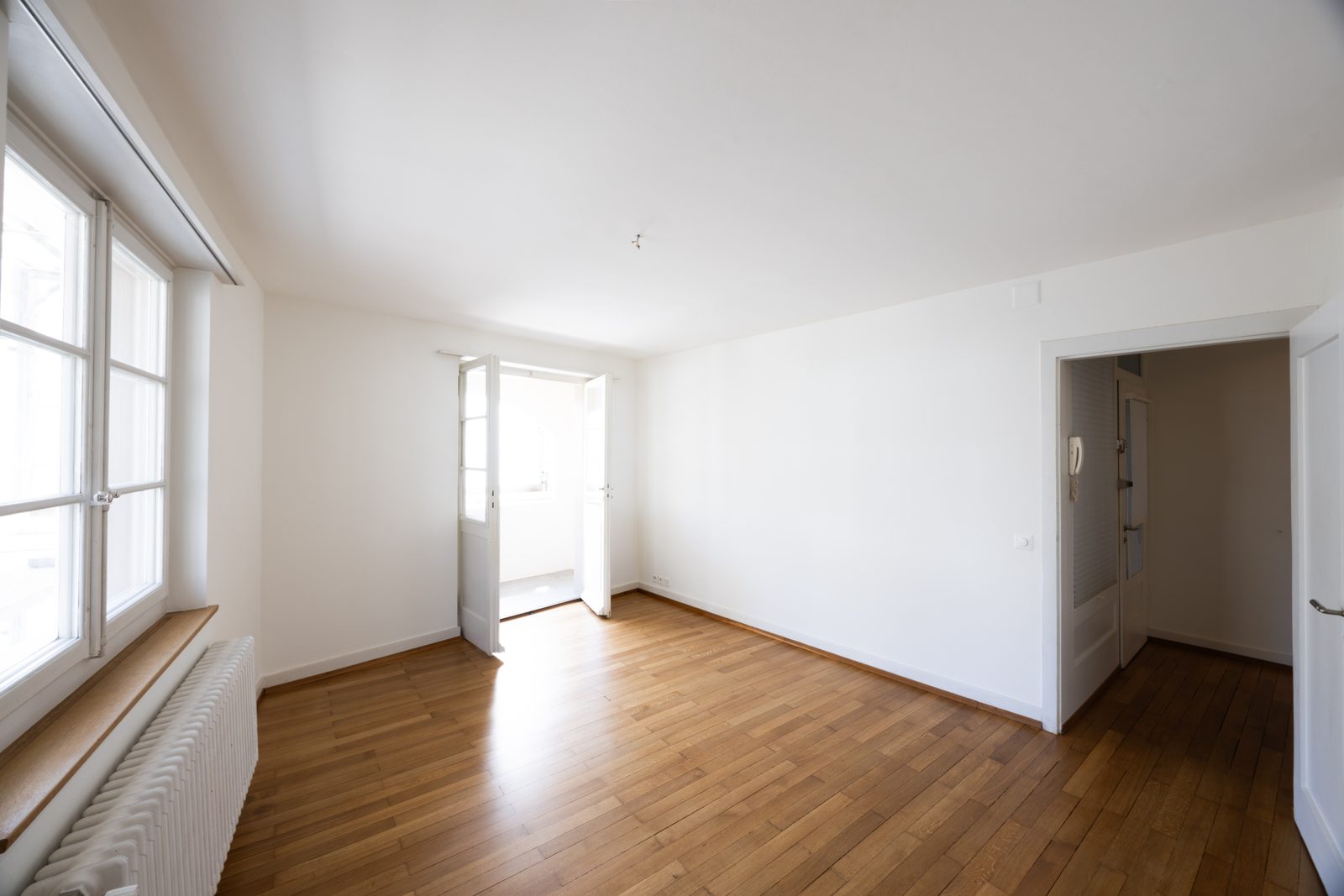 Helles Wohnzimmer mit Parkettboden und Zugang zum Balkon